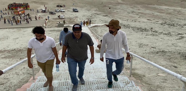 Trip host Mehdi Hussain in hte middle clad in polo and cap taking stairs to the Chandragup top