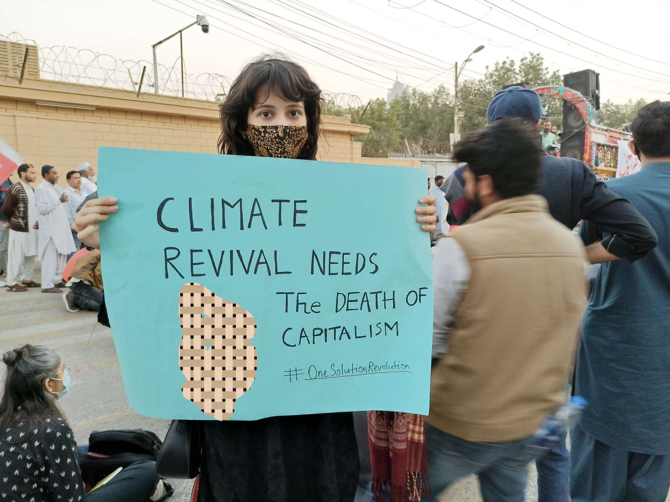 Participant holds placard that says capitalist interests thrive at the expense of climate sustainability 